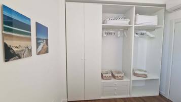 Ein Schlafzimmer mit einem weißen Kleiderschrank, einem Bett mit gestreifter Bettwäsche und zwei gerahmten Bildern an der Wand.