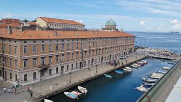 Ein Gebäude am Wasser mit einer langen Fassade, ein Hafen mit Booten und ein klarer Himmel.