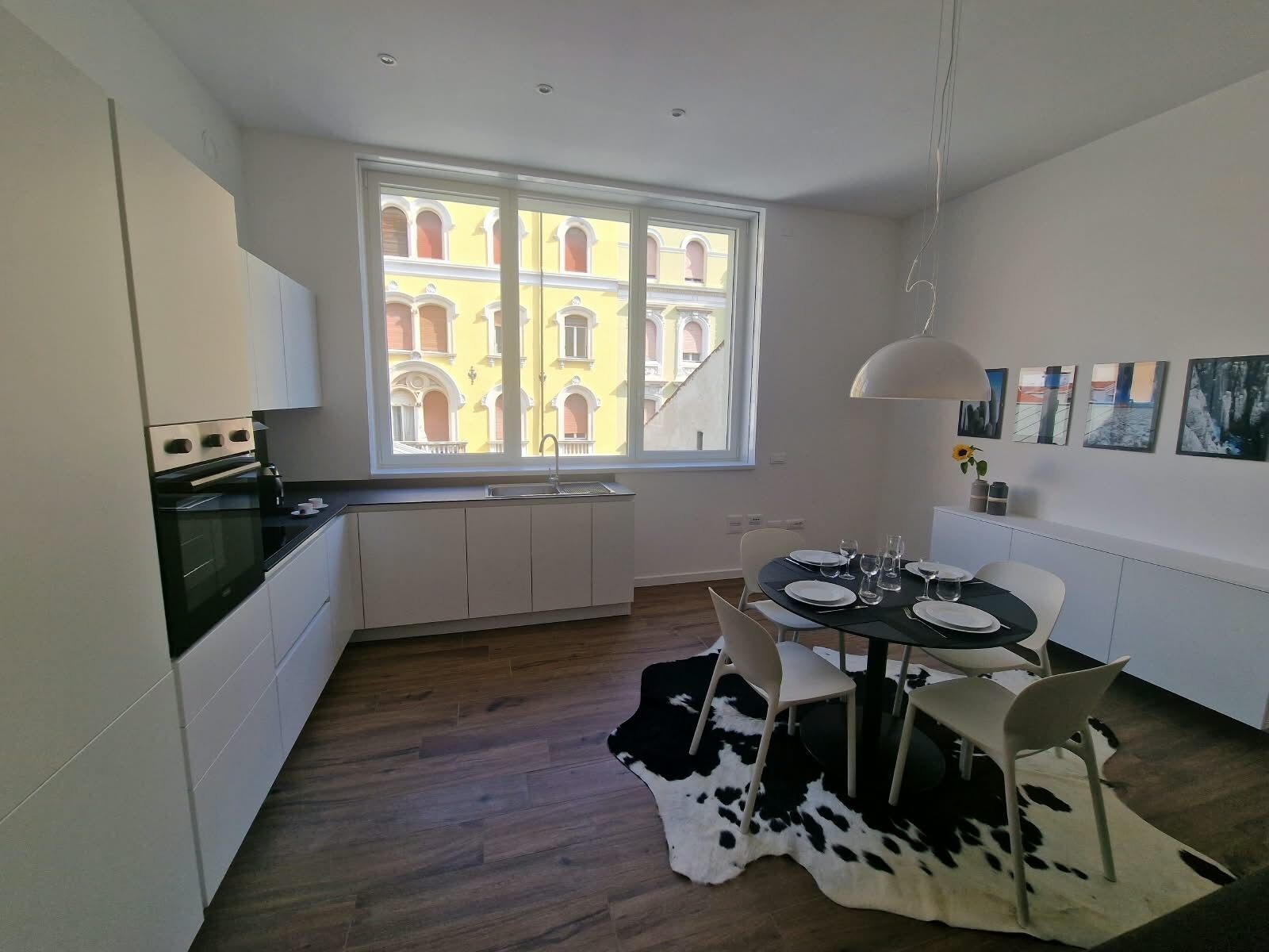 A modern kitchen with a window view, a dining area with a cowhide rug, and a table set for four.
