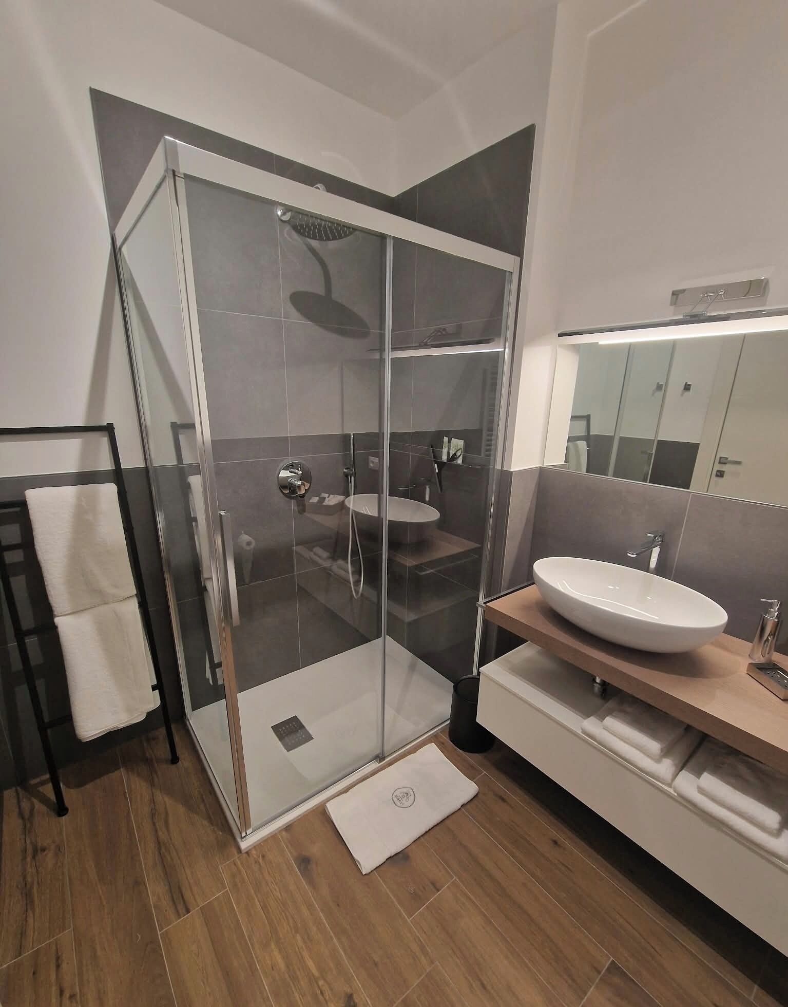 Une salle de bain moderne avec une douche à parois de verre, un lavabo blanc et un miroir.