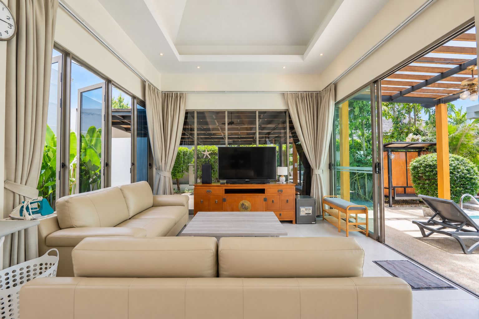 Una sala moderna con sofá, televisor y mueble de entretenimiento de madera.
