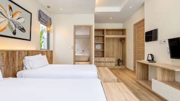 A modern hotel room with two beds, a walk-in closet, a shower area, and a TV mounted on the wall.
