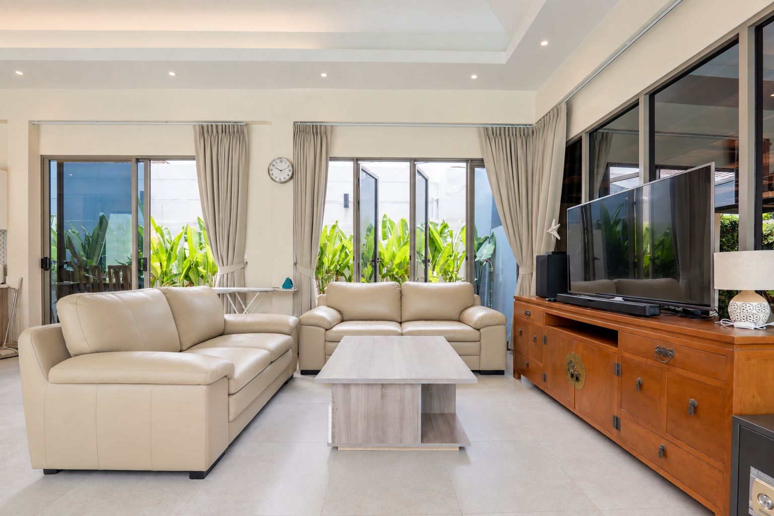 Una sala de estar moderna con un conjunto de sofás, una mesa de centro, un televisor y un mueble.