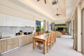 Cocina moderna con comedor, ventilador de techo y televisor en la sala.