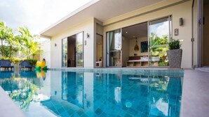 A modern hotel with a swimming pool, outdoor seating, and a patio area. - Kaizer Pool Villas (Thalang)