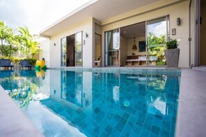 A modern hotel with a swimming pool, outdoor seating, and a patio area. - Kaizer Pool Villas (Thalang)