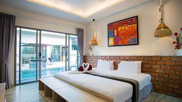 A hotel room with a large bed, a bench, a view of the pool, and a colorful artwork on the wall.