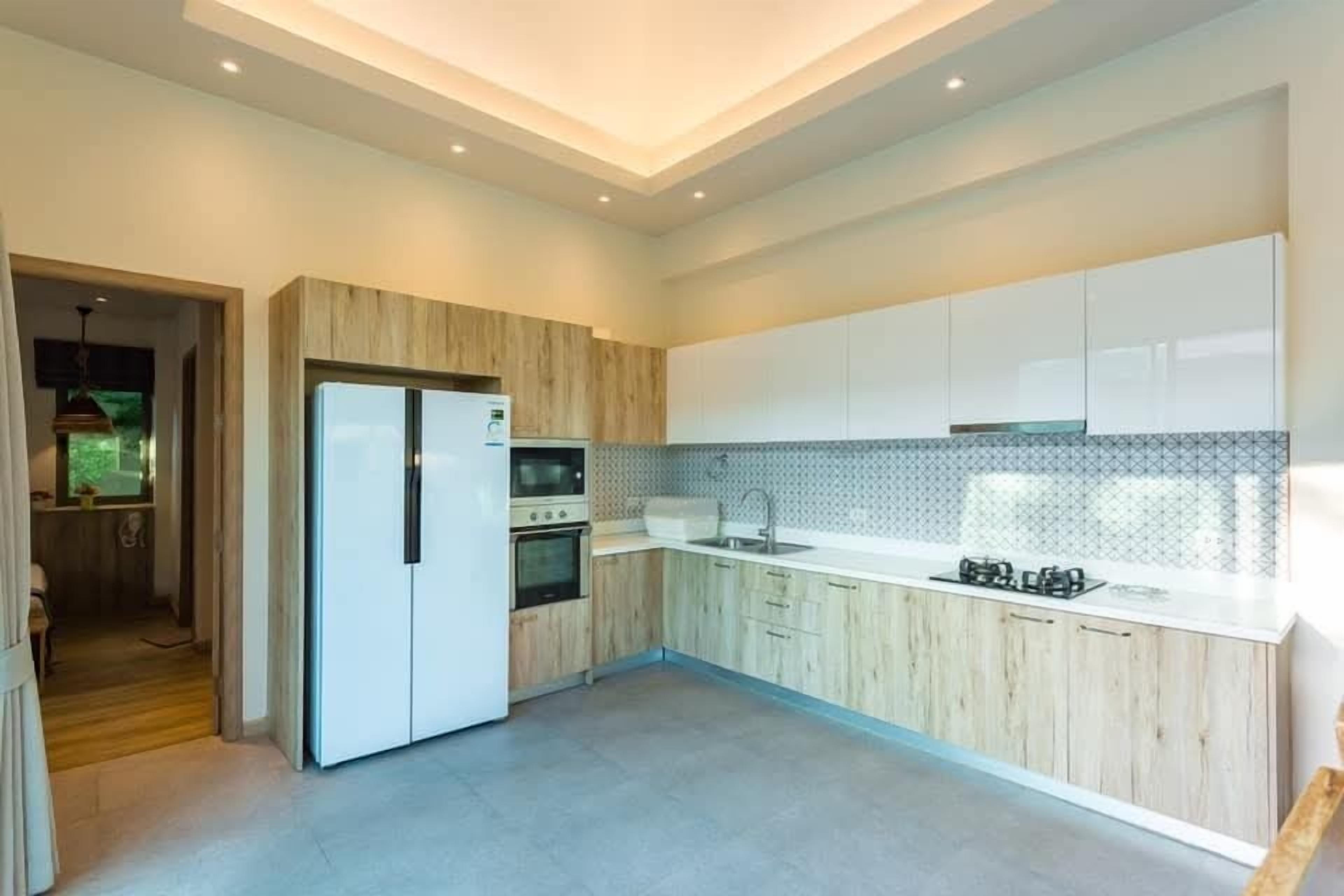 Una cocina moderna con gabinetes blancos, horno empotrado y pileta de acero inoxidable.