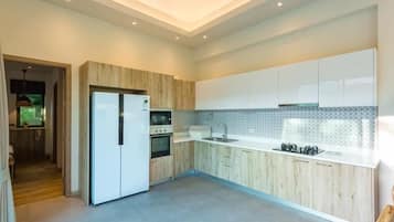 Una cocina moderna con gabinetes blancos, horno empotrado y pileta de acero inoxidable.