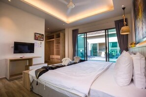 Una habitación de hotel con una cama grande, televisión, escritorio y puerta corrediza de vidrio a un balcón.