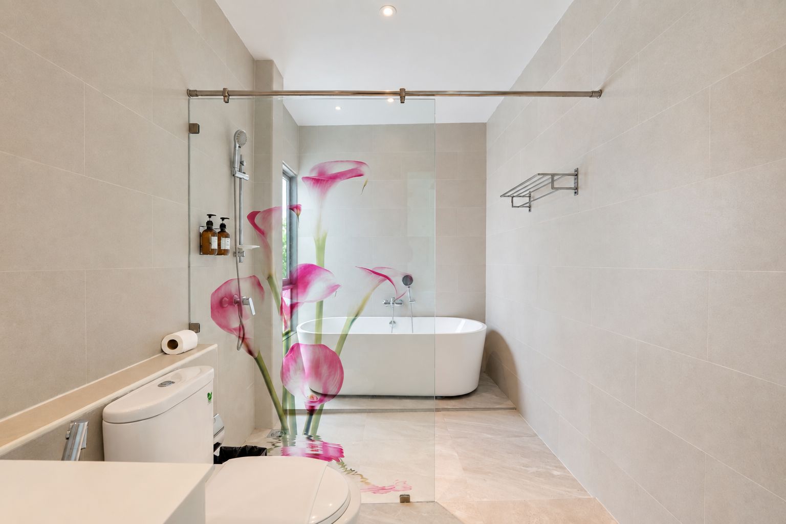 A modern bathroom with a glass shower enclosure, a freestanding bathtub, and a toilet.