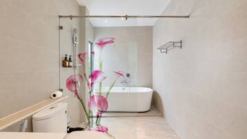 A modern bathroom with a glass shower enclosure, a freestanding bathtub, and a toilet.