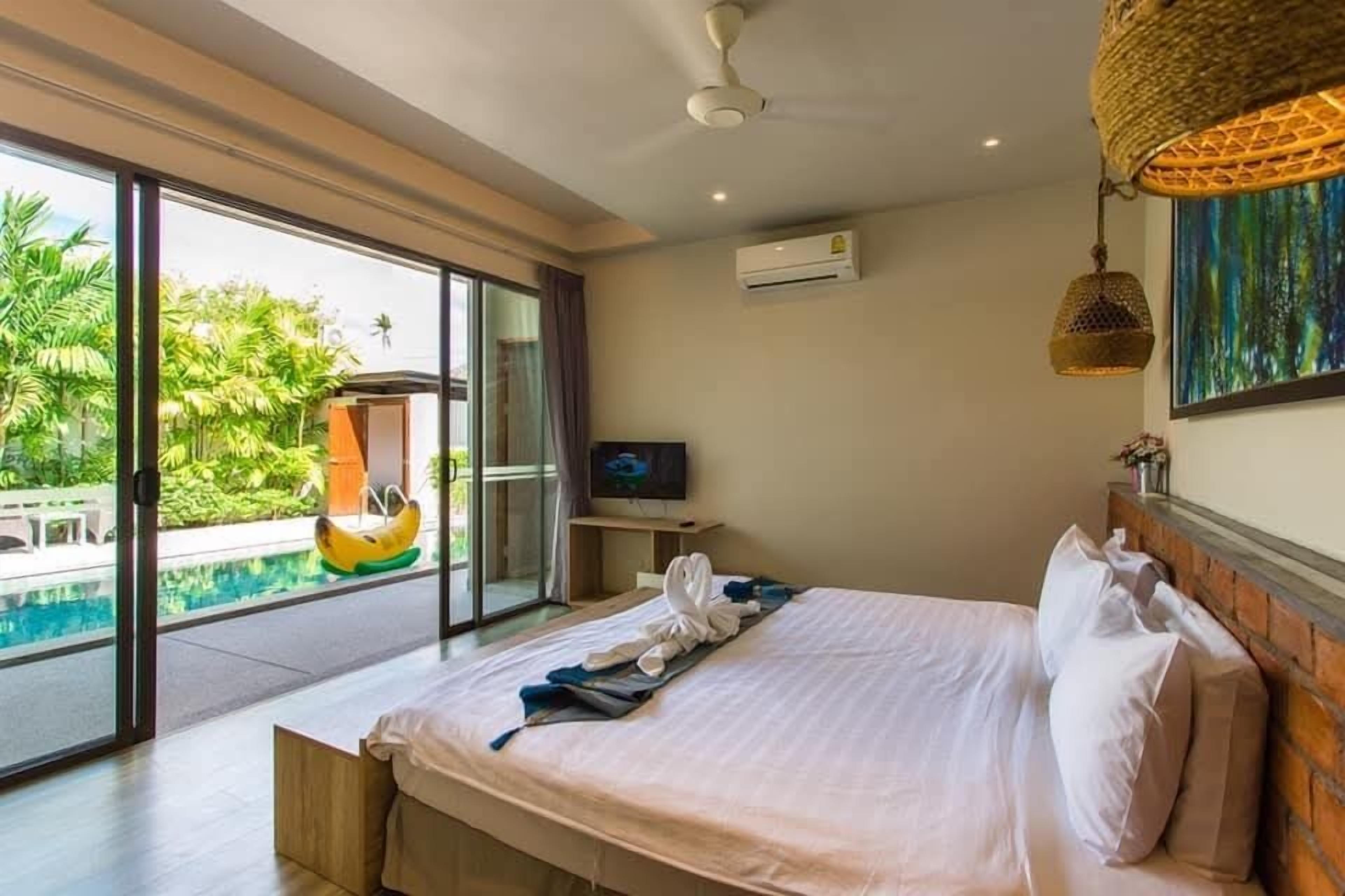 Habitación de hotel con cama, televisión, aire acondicionado y vistas a una piscina.