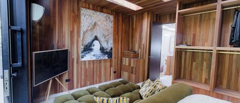 Una habitación moderna con detalles de madera, una cama grande, un sofá, un televisor y un cuadro de una cueva.