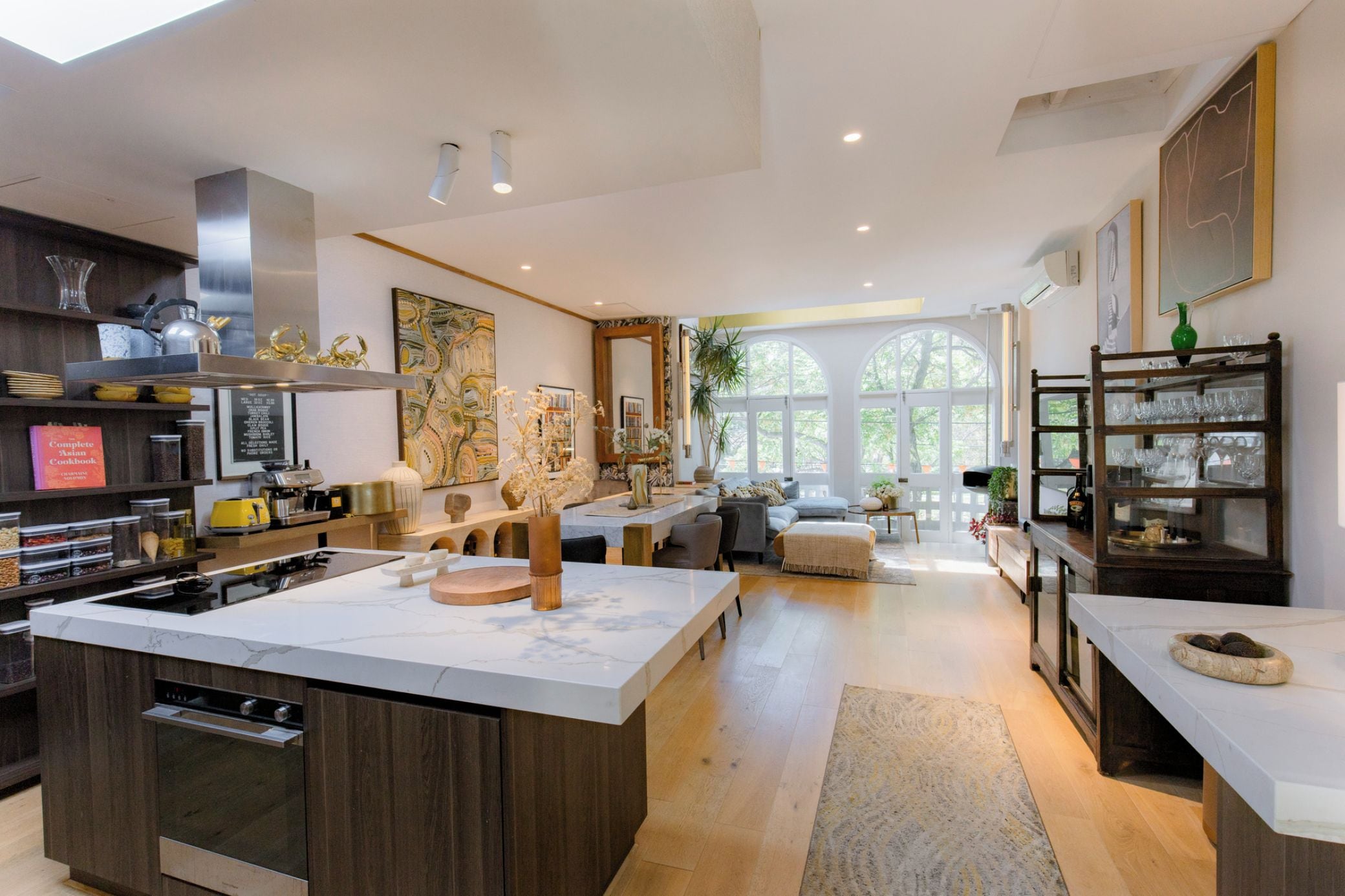 A modern kitchen with an island, built-in appliances, and a dining area with a sofa and table.