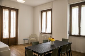 A room with a dining table, chairs, a radiator, and windows with curtains. - Hearth City Center Milan (MI)