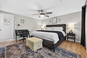 Une chambre d’hôtel équipée d’un lit, d’un bureau, d’une chaise, de tables de chevet et d’un ventilateur de plafond.