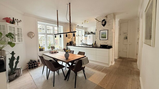 A modern kitchen with a dining area, featuring a wooden table, chairs, and a large window.