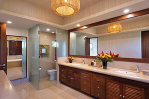 Une salle de bain moderne dotée d’un grand miroir, de deux vasques et d’une douche à parois de verre.