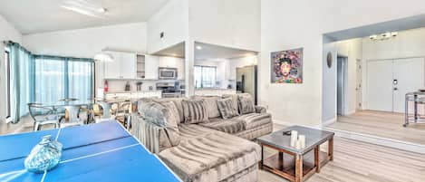 A modern living room with a sectional sofa, a coffee table, and a dining area with a blue table.
