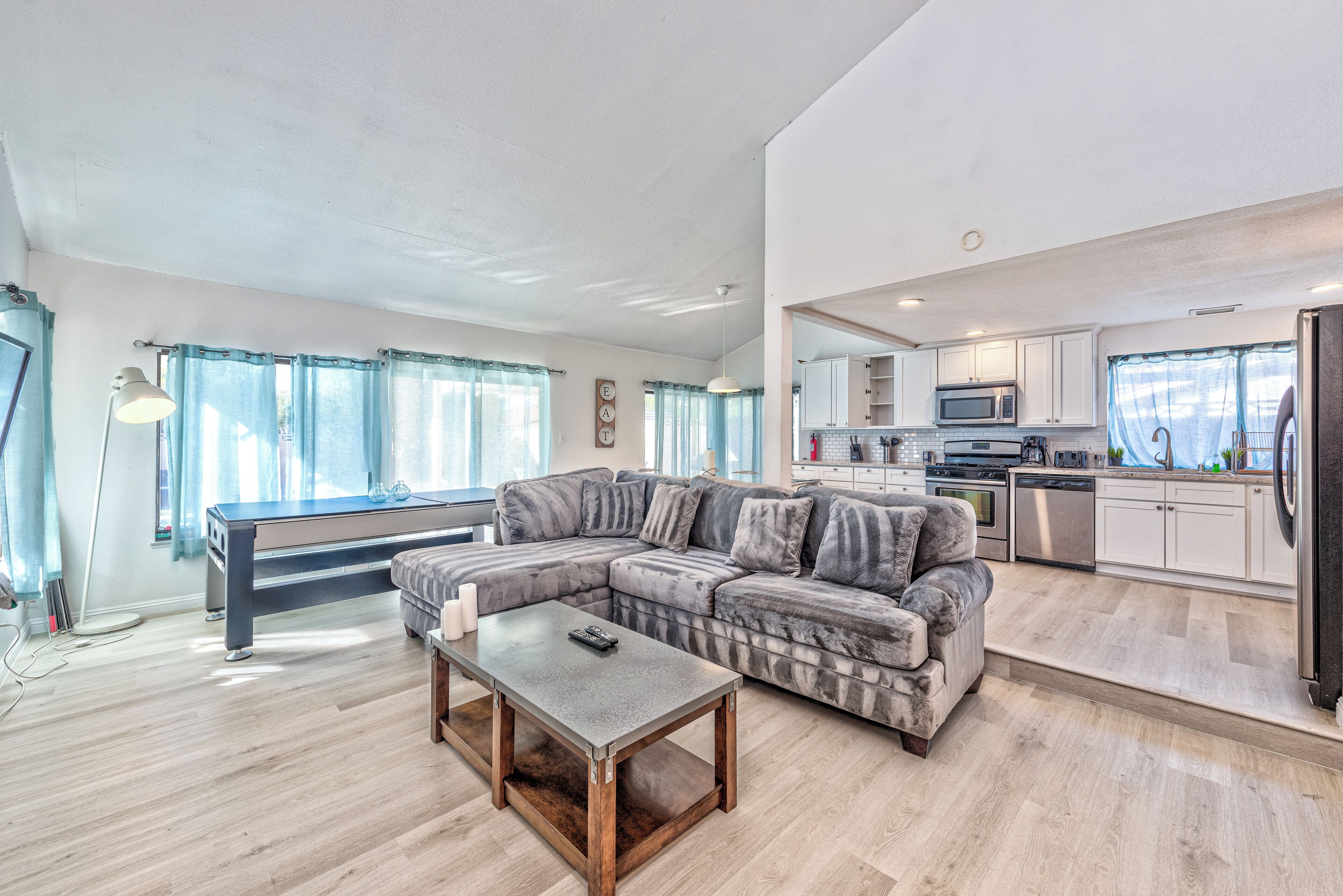 A spacious living area with a sectional sofa, a pool table, and a kitchen with modern appliances.