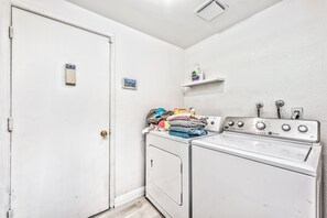 A laundry room with a washer and dryer, a door, a small shelf with laundry supplies, and a picture on the wall. - Las Vegas Boutique Villa with Pool & BBQ (Las Vegas)