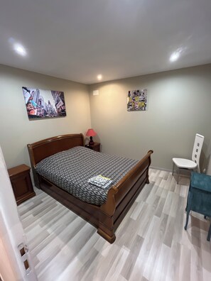 Ein Schlafzimmer mit einem hölzernen Bett, einem Nachttisch, einem Stuhl und zwei Bildern an der Wand.