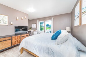 A bedroom with a bed, a TV, a desk, and a window with a view. - Private Hot Tub, Large Fenced Yard, No Pet Fee (Colorado Springs)