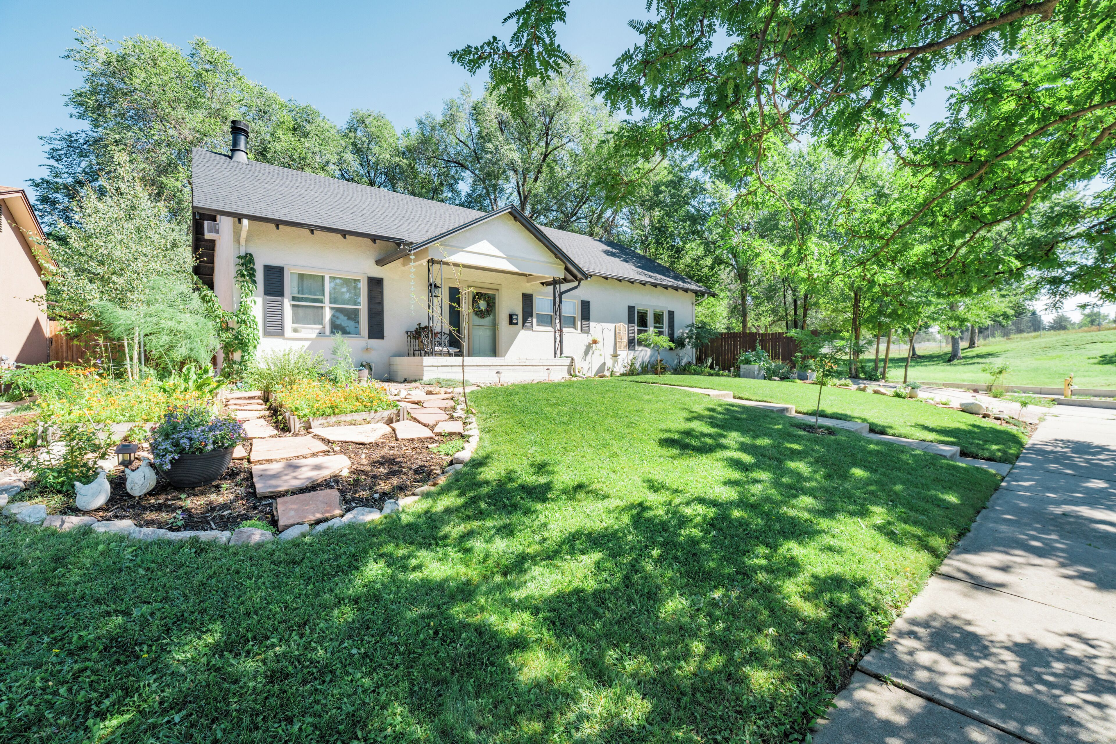 A residential house with a front yard, a paved driveway, and a lawn.