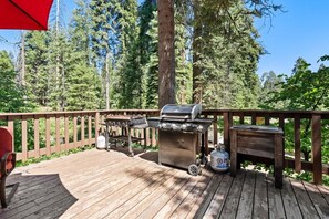 Une terrasse en bois équipée d’un barbecue et d’une bouteille de gaz.