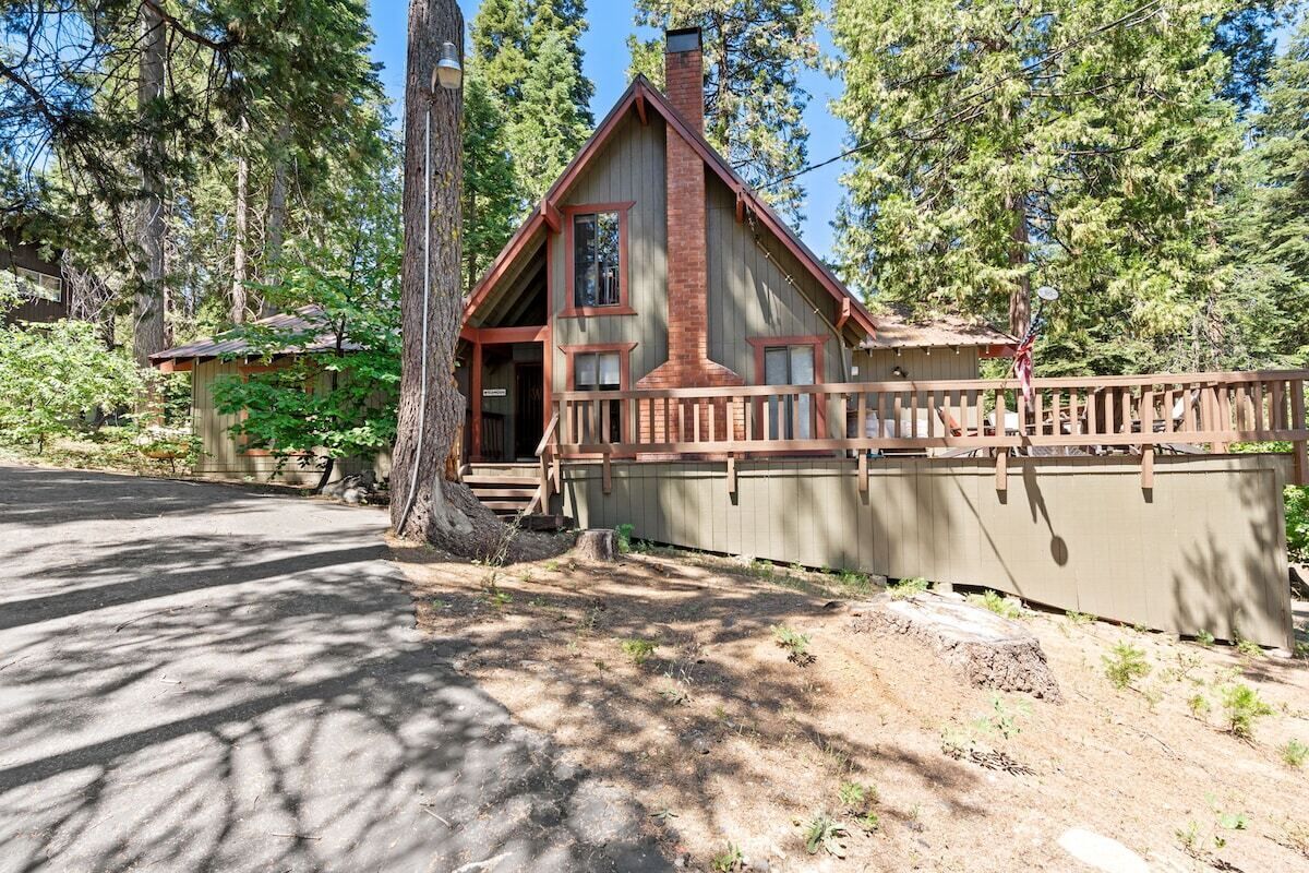 A cabin with a wooden exterior, a chimney, and a porch.