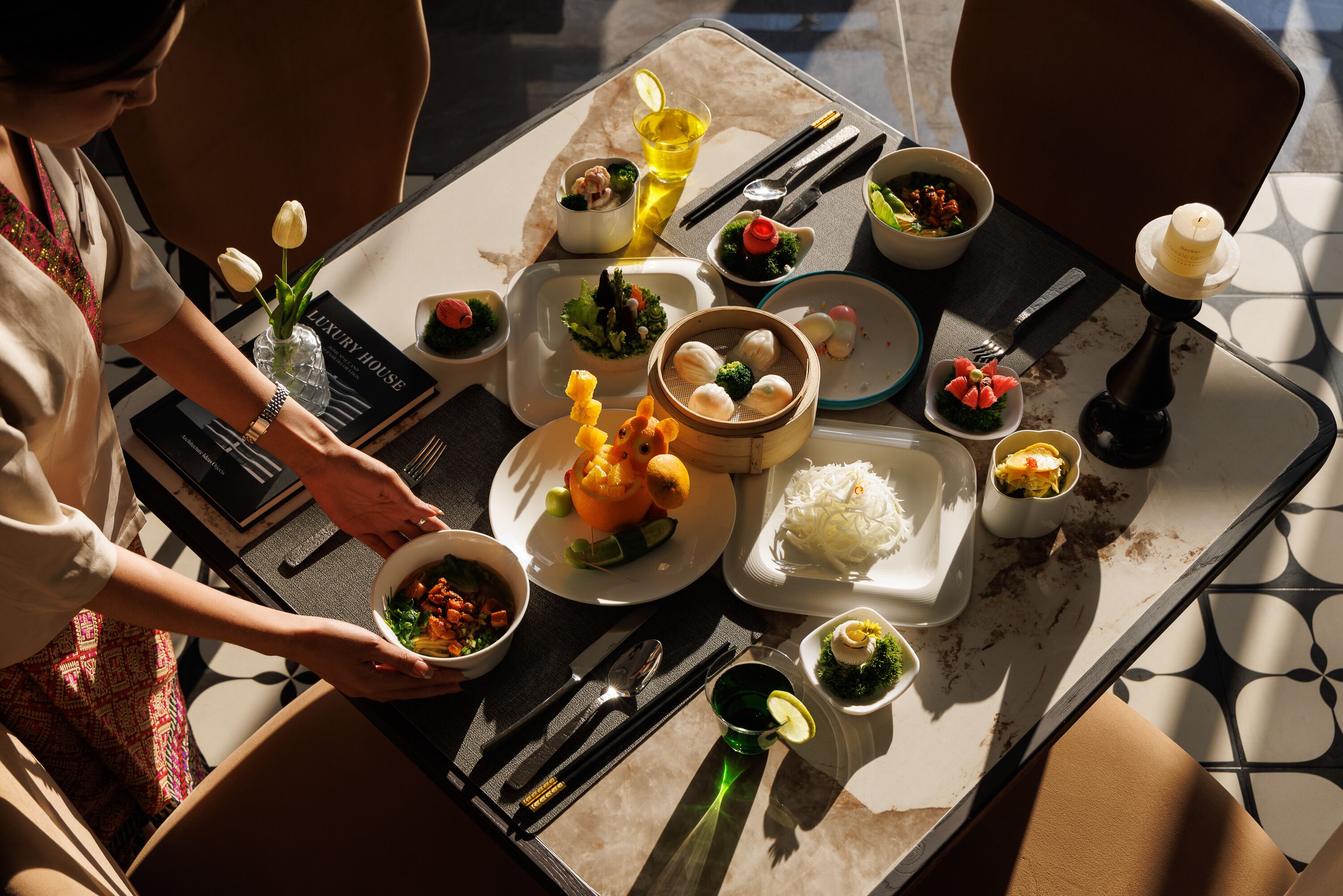 A table set with various dishes, utensils, and a book titled 'LUXURY HOUSE'.