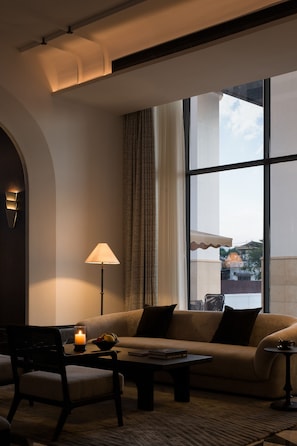 A modern living room with a sofa, armchairs, a coffee table, and a lamp.