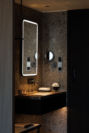 Een moderne badkamer met een grote spiegel, een wastafel, een handdoekrek en een toilet.
