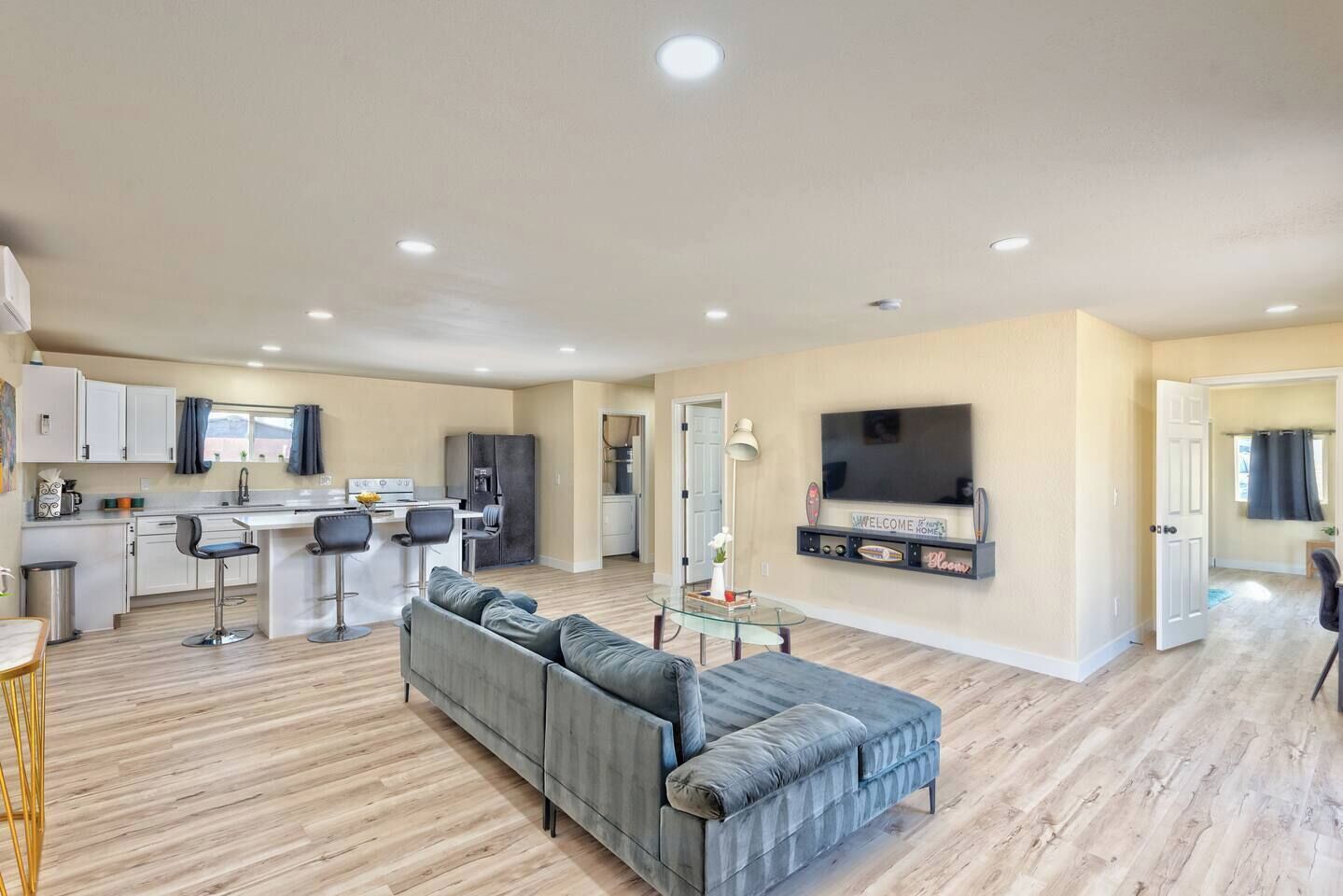 A modern apartment with a kitchen, dining area, living room, and a TV mounted on the wall.