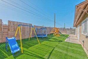 A fenced backyard with artificial grass, a swing set, a trampoline, and a play structure. - villa for families pool/jacuzzi/playground (Las Vegas)