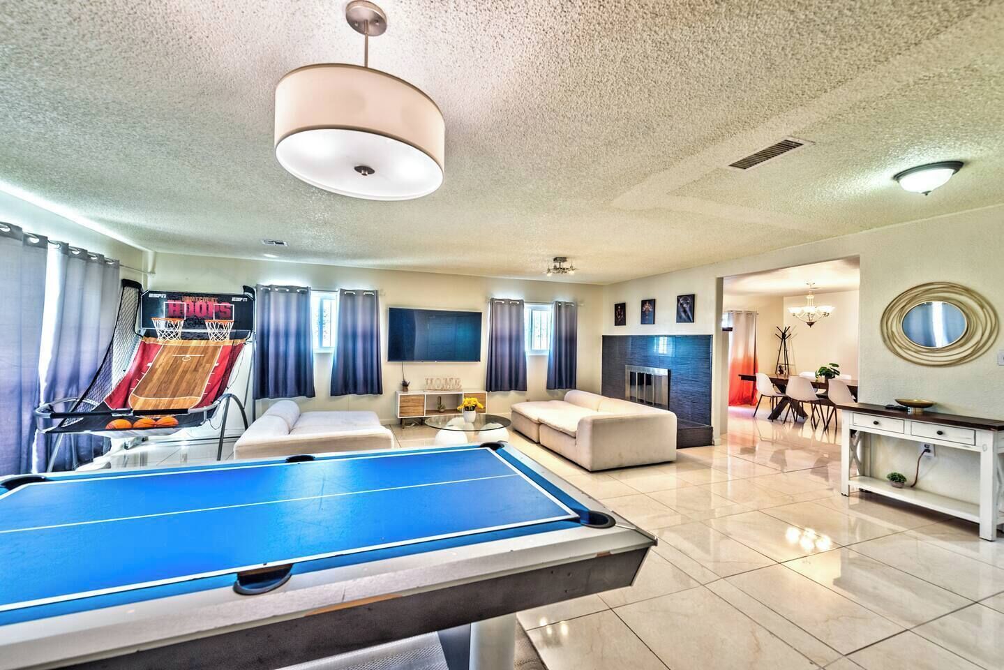 Un grand espace de vie comprenant une table de billard, un canapé, un téléviseur et une cheminée.