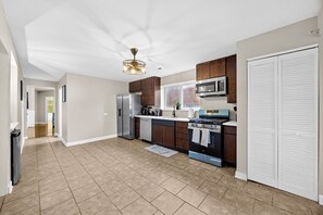 A modern kitchen with a stainless steel refrigerator, a microwave, a stove, and wooden cabinets. - Your Parkside Executive Retreat + Dedicated Office (Chicago)