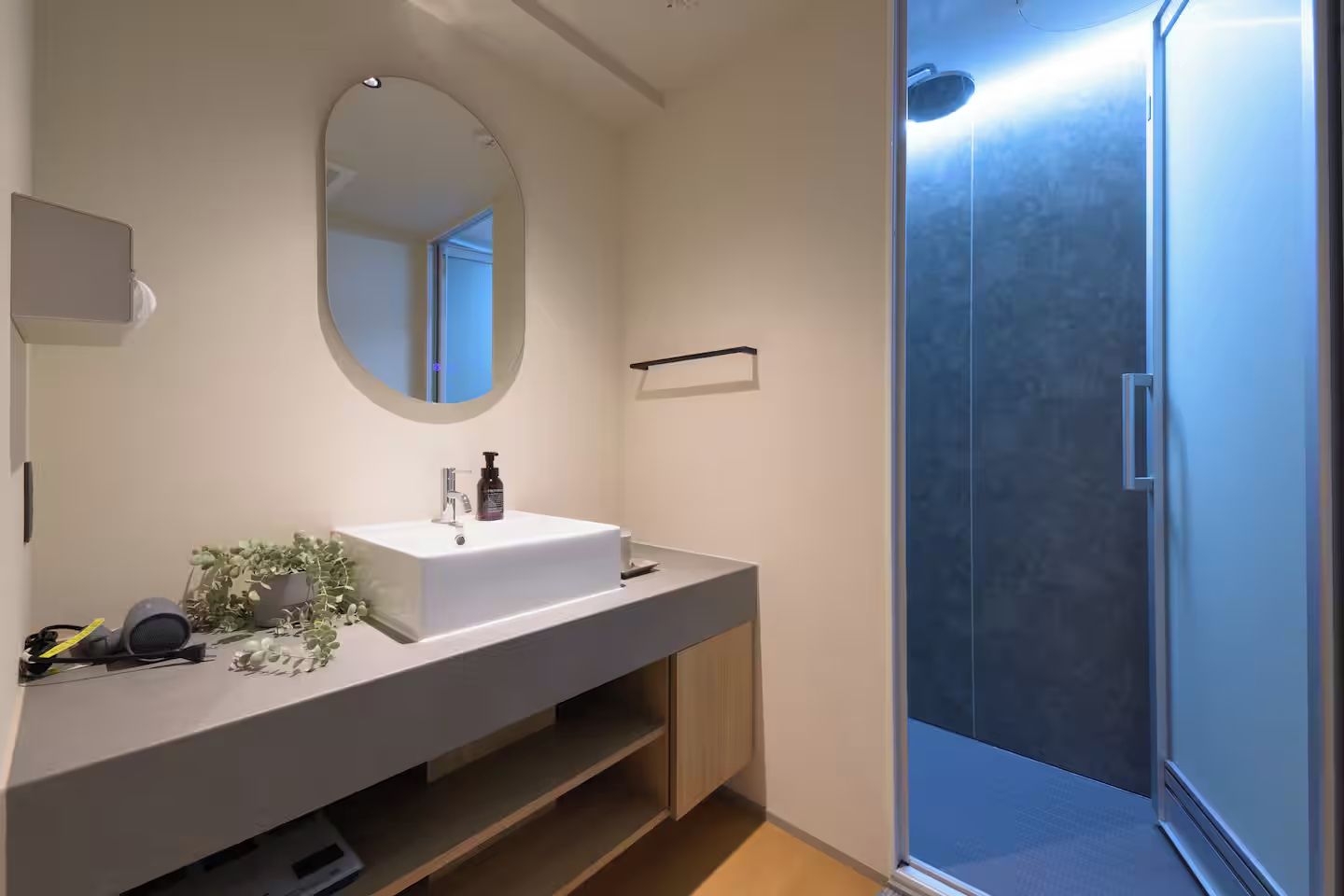 A modern bathroom with a white sink, mirror, and shower.