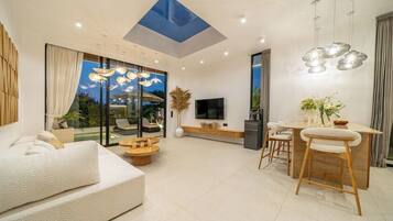 A modern living room with a sofa, dining area, and a TV.