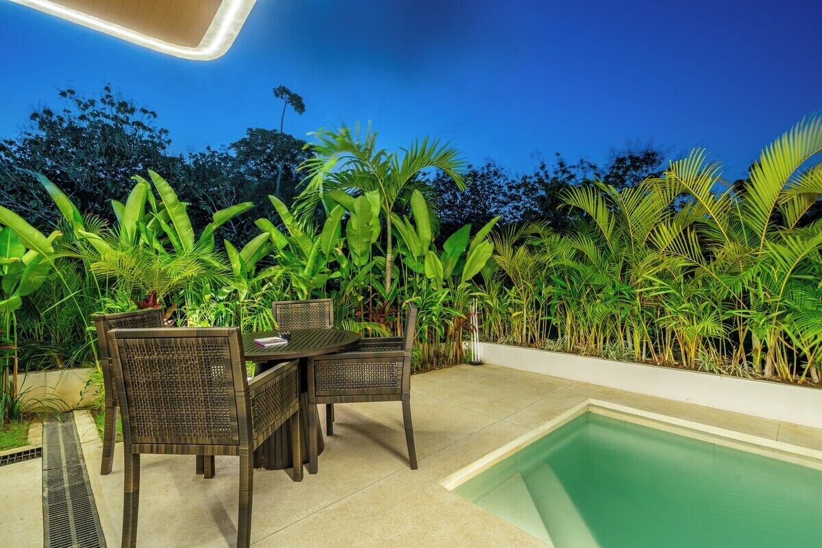 An outdoor seating area with a pool, surrounded by lush tropical plants.