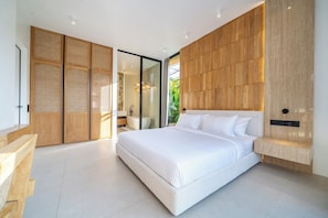 A modern bedroom with a large bed, wooden panel walls, and a glass door leading to a bathroom. - Brand New Villa+Huge Pool+Beach Access+South Kuta (Badung Regency)