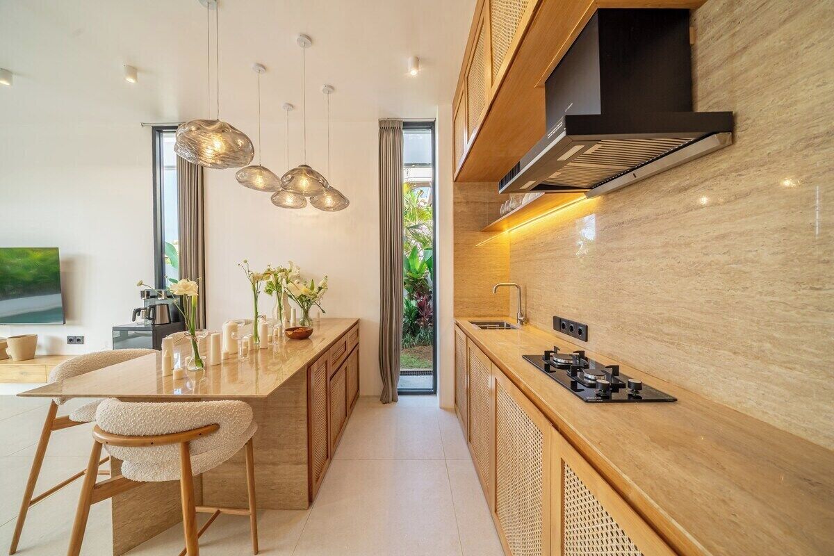A modern kitchen with a central island, pendant lighting, and a view to the outdoors.