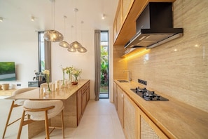 A modern kitchen with a central island, pendant lighting, and a view to the outdoors. - Brand New Villa+Huge Pool+Beach Access+South Kuta (Badung Regency)