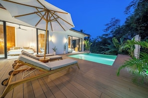 Et moderne hus med swimmingpool, træterrasse og liggestole.