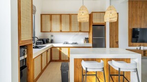 Una cocina moderna con armarios de madera, una isla central con taburetes de bar y un televisor integrado.
