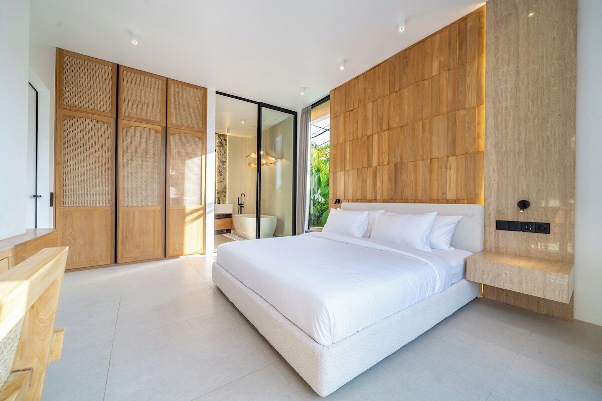A modern bedroom with a large bed, wooden paneling, and a view of the outdoors.
