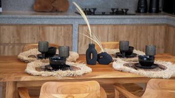 Ein Holztisch mit schwarzen Schüsseln und gewebten Tischsets, vor einer Wand aus Holzverkleidung und Stein.