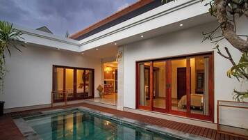 Ein modernes Haus mit Swimmingpool, großen Schiebetüren und einer Terrassenfläche.