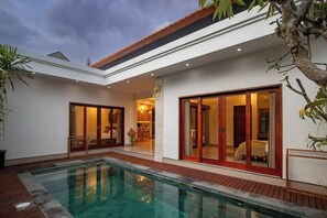 Ein modernes Haus mit Swimmingpool, großen Schiebetüren und einer Terrassenfläche.